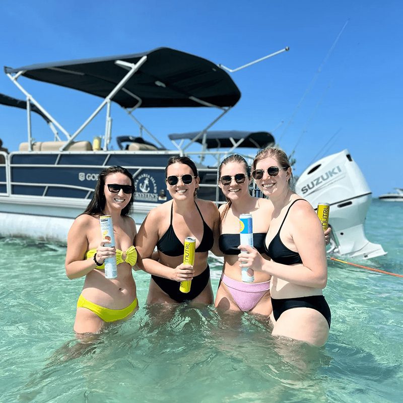 Friends holding drinks in ocean water