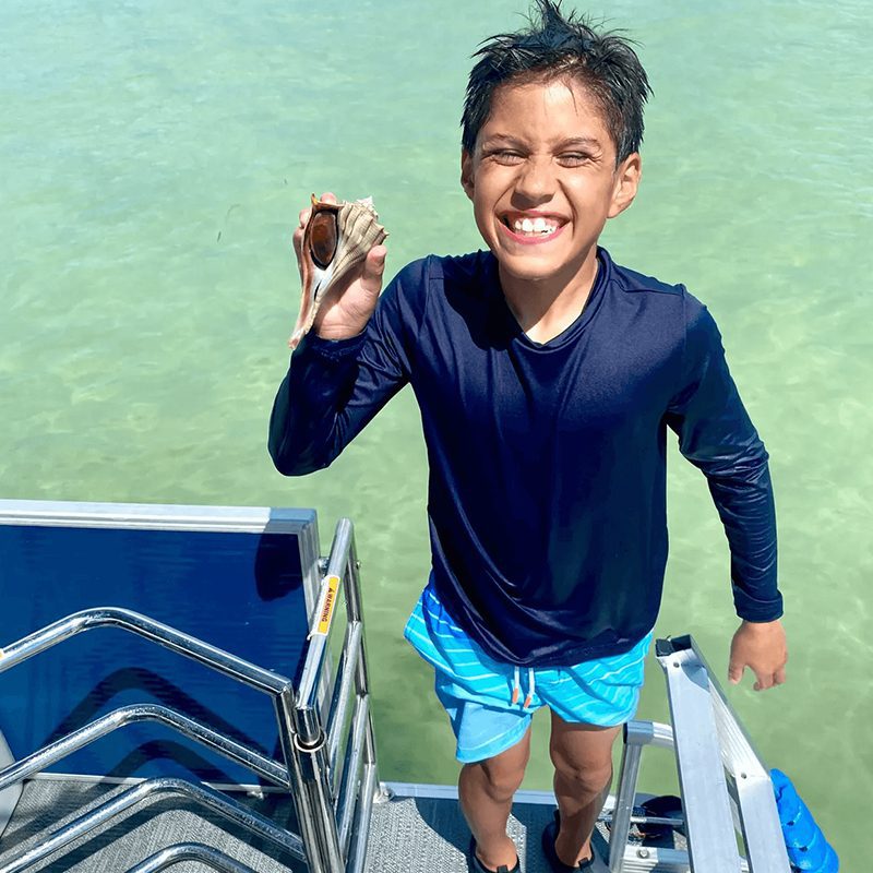 Boy holding a seashell on boat