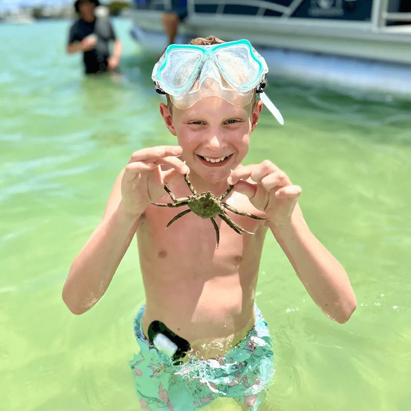 Boy holding a crab in water