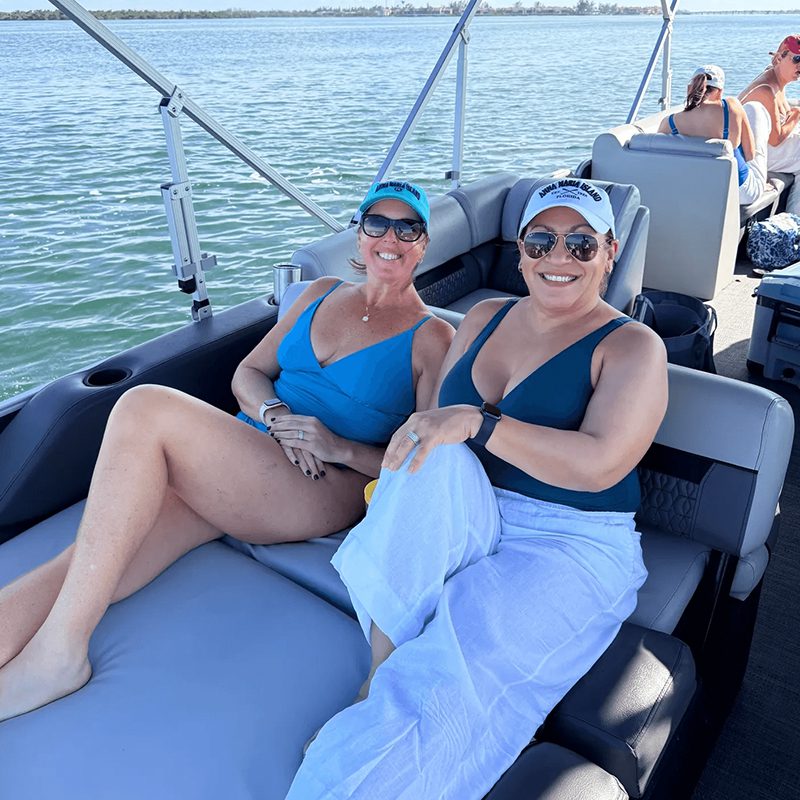 Smiling women in blue swimsuits on boat