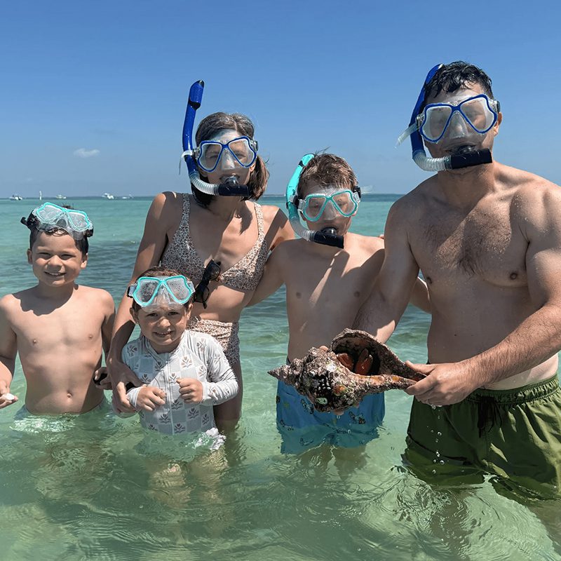 Family snorkeling with large conch shell
