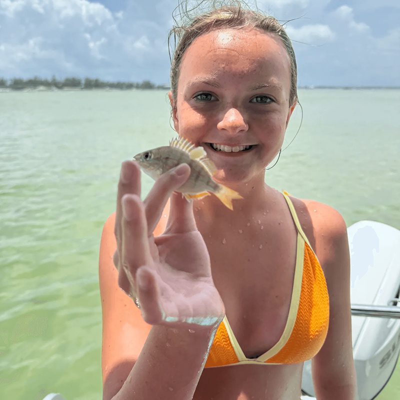 Girl holding small fish on boat