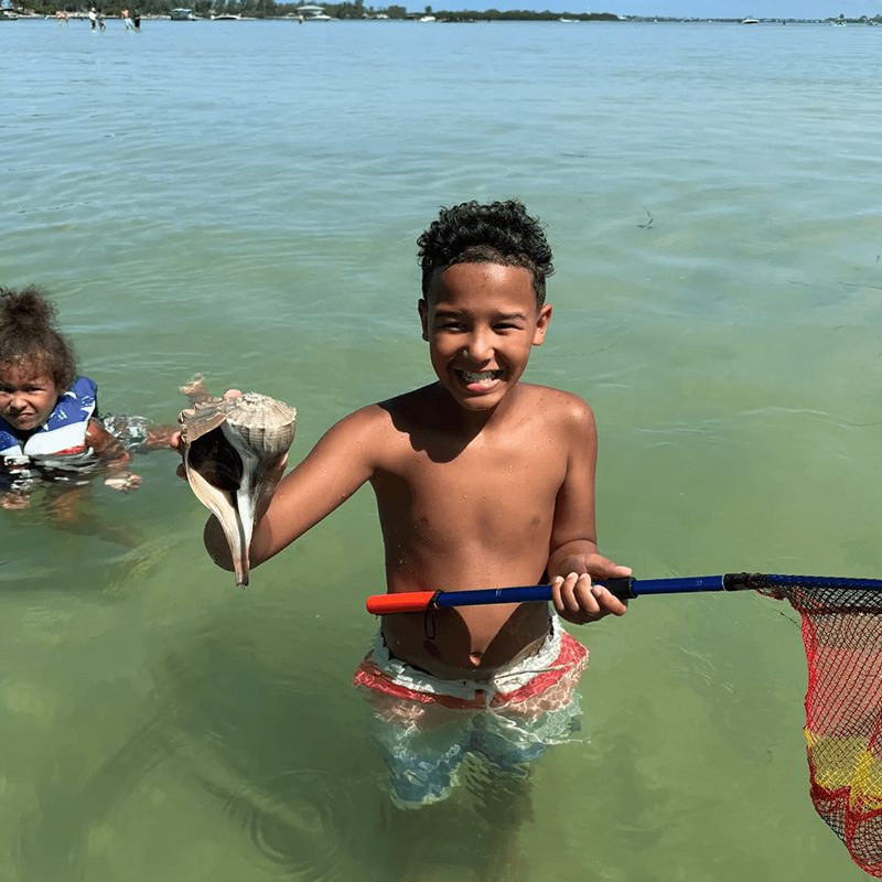 Boy holding seashell in the water