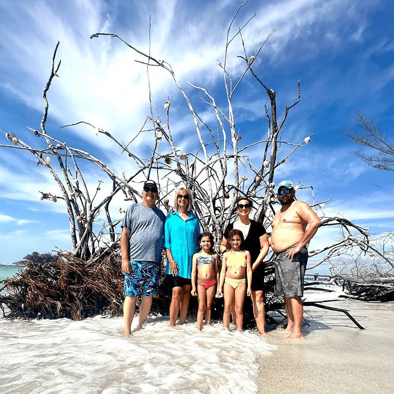 Family posing on a beach with driftwood