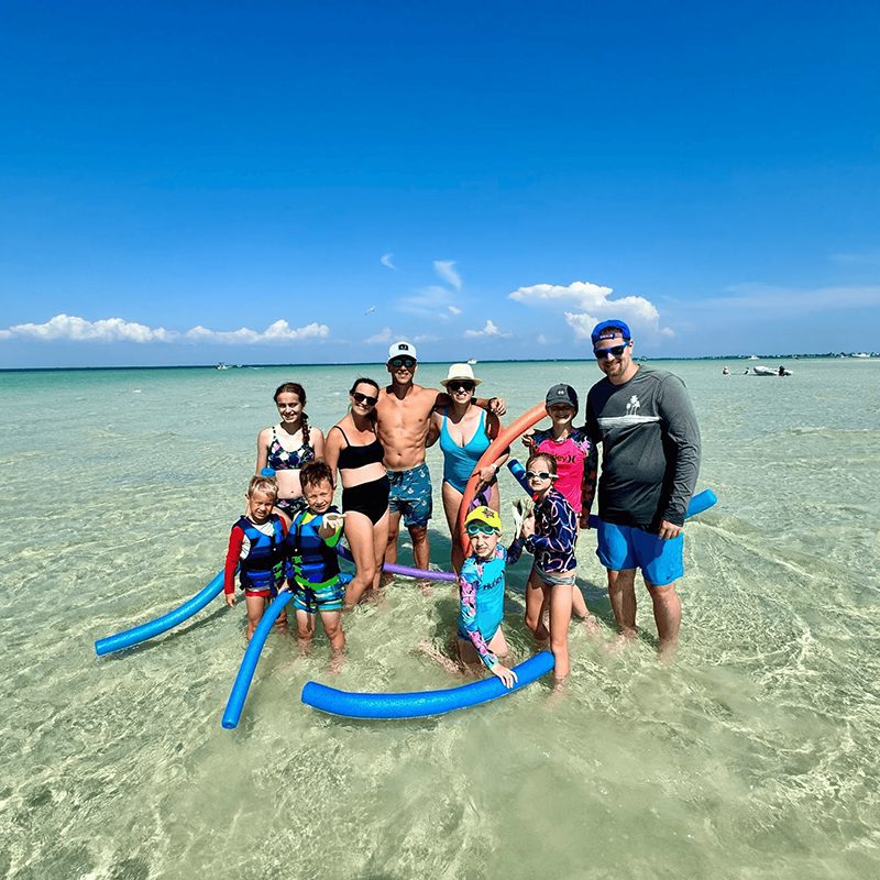 Group enjoying beach with pool noodles