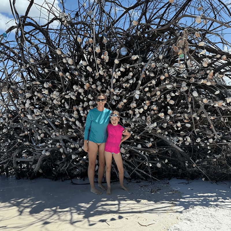 Two individuals near a seashell tree