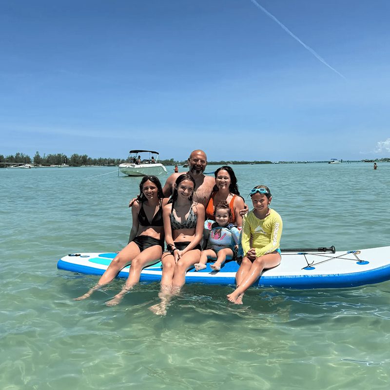 Group posing on paddleboard in clear water