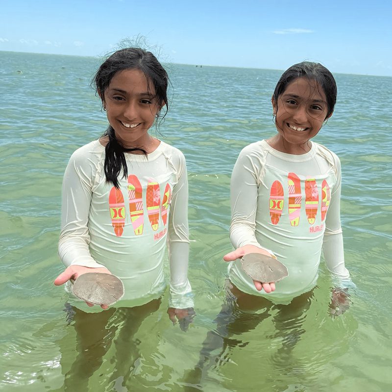 Twin sisters smiling in the sea
