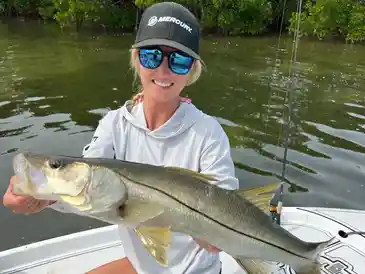 Woman displays snook by the water