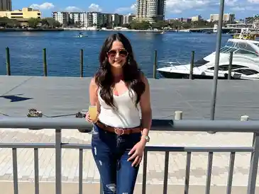 Smiling woman holding drink by marina