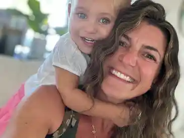 Smiling woman with child hugging her neck.